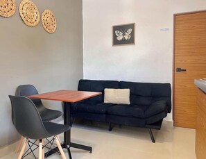 A room with a dark blue sofa, a wooden table, and two black chairs. - Downtown Cancún Studio · WiFi & Smart TV (Cancún)