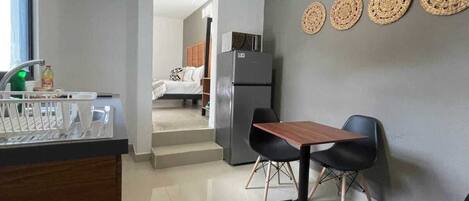 A compact kitchen with a dining area, a refrigerator, and a window.