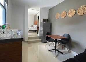 A compact kitchen with a dining area, a refrigerator, and a window. - Downtown Cancún Studio · WiFi & Smart TV (Cancún)