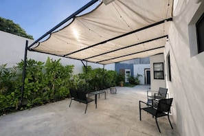 An outdoor patio with a canopy, seating, and potted plants. - Downtown Cancún Studio · WiFi & Smart TV (Cancún)