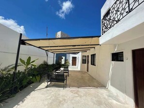 A covered patio area with a table and chairs, a concrete floor, and a view of a building in the background. - Downtown Cancún Studio · WiFi & Smart TV (Cancún)