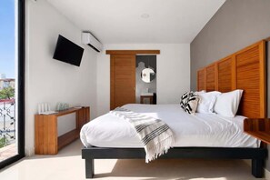 A modern bedroom with a bed, a TV mounted on the wall, and a wooden headboard. - Downtown Cancún Studio · WiFi & Smart TV (Cancún)