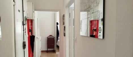 A hallway with wooden flooring, white walls, and a mounted air conditioner.