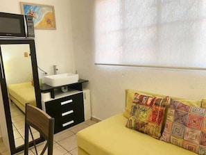 A room with a bed, a bedside table, a chair, a sink, and a window with blinds. - Central 1BR Apt + Rooftop, Downtown Cancun (Cancún)