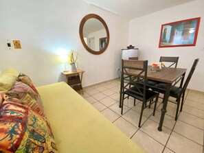 A room with a bed, a dining table with chairs, a mirror, and a framed picture on the wall. - Central 1BR Apt + Rooftop, Downtown Cancun (Cancún)