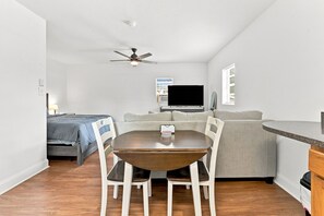 Un espacio habitable compacto con una mesa de comedor, sillas, un sofá, un televisor y un ventilador de techo.