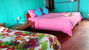 Quarto com duas camas, uma com colcha florida e a outra com colcha rosa.