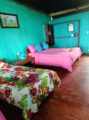 Una habitación con dos camas, una con cubrecama floral y otra con cubrecama rosa.