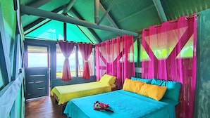 Una habitación con dos camas, piso de madera y techo de metal verde.