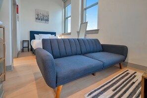 Un salon moderne avec un canapé bleu, un plancher en bois et un tapis à rayures.