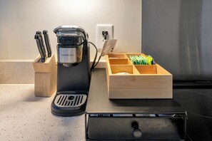 Eine Kaffeemaschine mit Kaffeepadhalter und eine Holzkiste mit Kaffeekapseln auf einer Küchenarbeitsplatte.