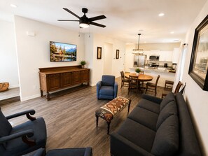A modern living room with a sofa, chairs, a coffee table, and a dining area with a table and chairs.