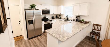 A modern kitchen with white cabinetry, stainless steel appliances, and a granite countertop.