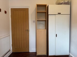 Een kamer met een houten deur, een witte radiator en een witte kast.