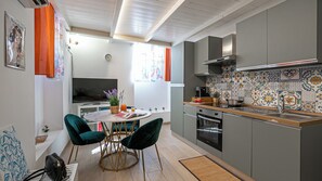 Una cocina moderna con comedor, que incluye un televisor, un reloj y un salpicadero colorido.