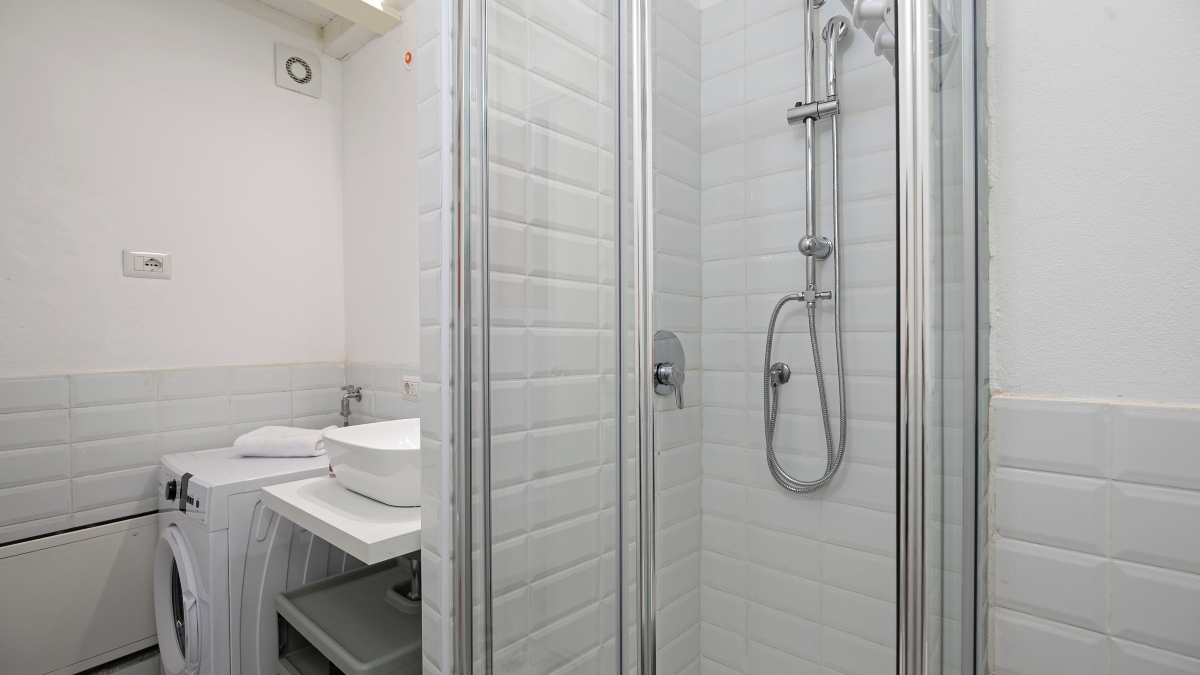 Ein Badezimmer mit Duschkabine, Waschbecken und Waschmaschine.