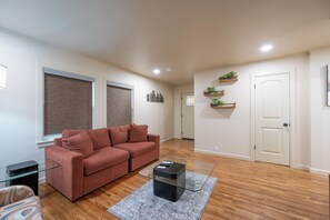 A living room with a red sofa, a glass coffee table, and a gray rug. - Luxury Apartment C on TU Campus and 2 miles to downtown (Tulsa)
