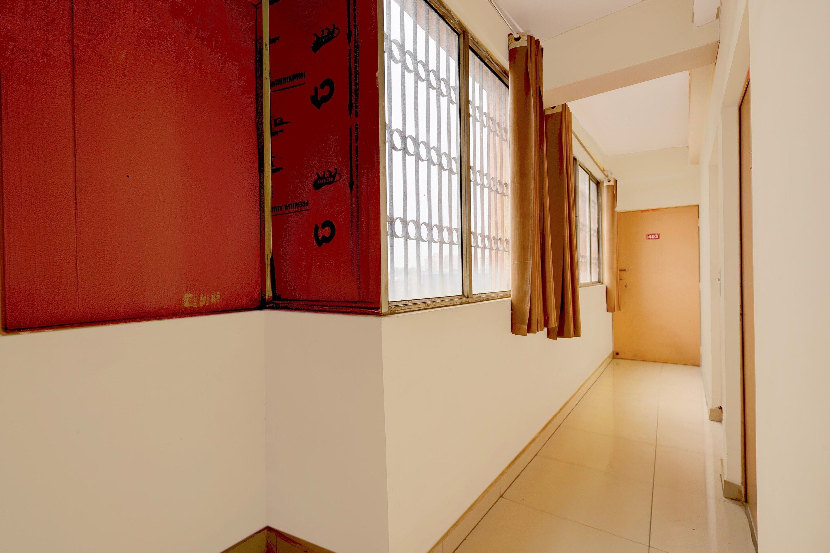 A corridor with a red door, a window with metal bars, and a door marked with the number 403.