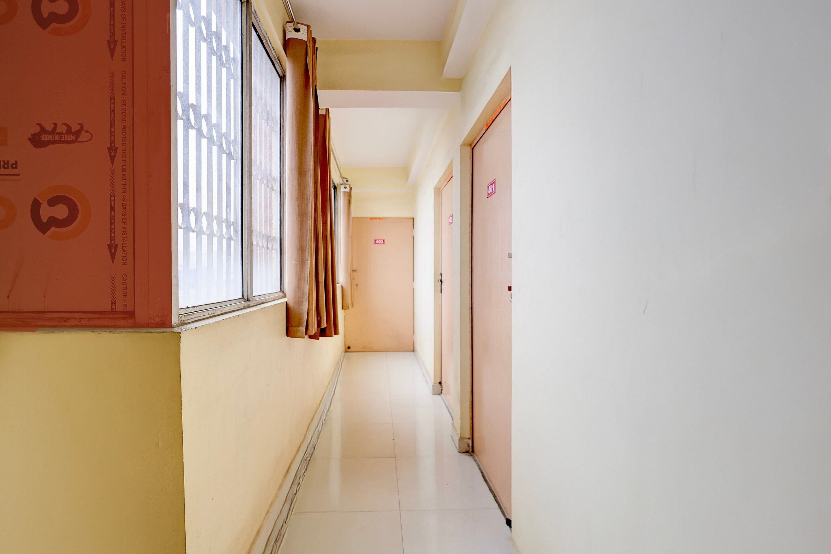 A corridor with doors marked 403 and 404, a window with blinds, and a wall with a caution sign.