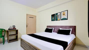 A hotel room with a bed, a desk, a chair, and artwork on the wall.