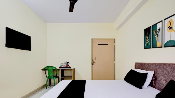 Una habitación de hotel con una cama, una silla, una mesita con una tetera y una puerta.