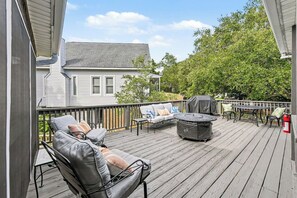 Una terraza de madera con mobiliario exterior, incluyendo un sofá y sillas, y una mesa redonda.