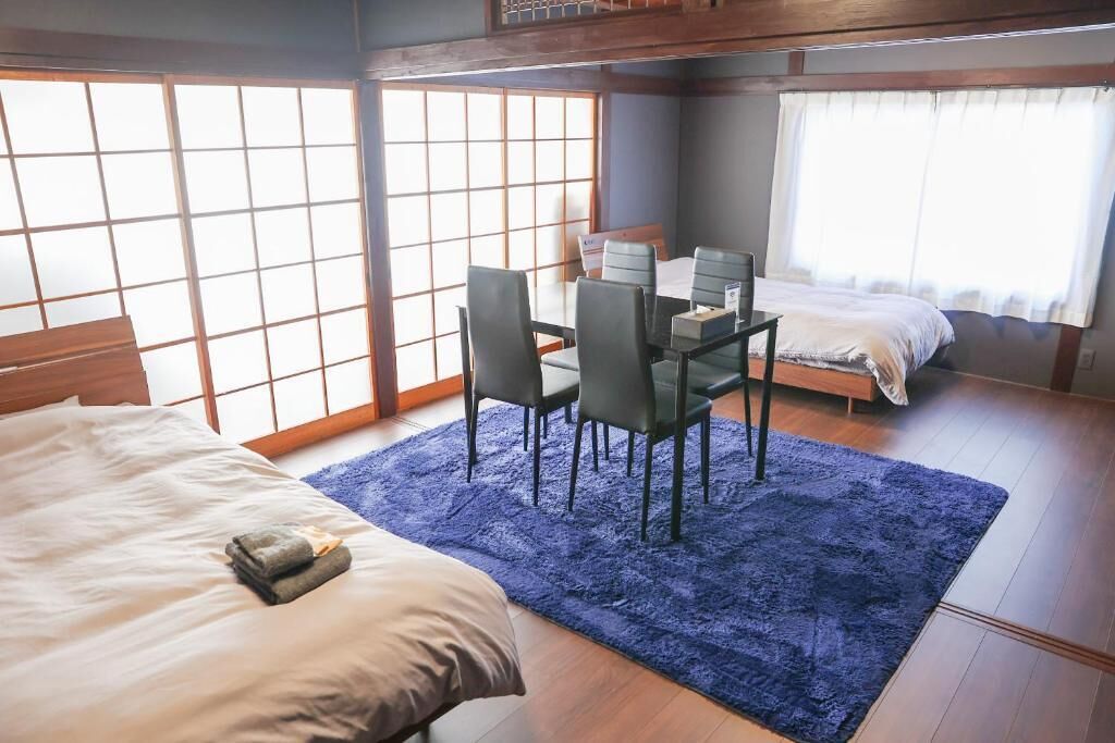 Una habitació amb un llit, una taula de menjador amb caires, una taula petita amb una cadira i una finestra amb vistes.
