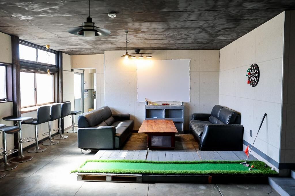 A modern lounge area with leather sofas, a dartboard, and a large whiteboard.