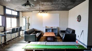 A modern lounge area with leather sofas, a dartboard, and a large whiteboard.