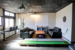 A modern lounge area with leather sofas, a dartboard, and a large whiteboard. - Udo Torii Gate Stay YOI (Nichinan)