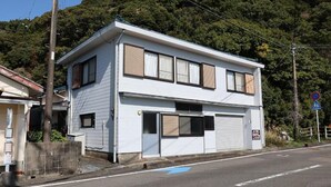 A two-story building with a garage door, located at a street corner with a blue directional arrow on the road.