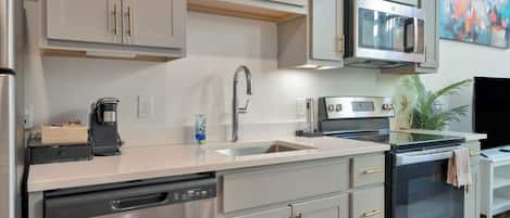 Cocina moderna con electrodomésticos de acero inoxidable, lavavajillas y microondas.