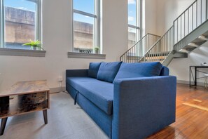 A modern living room with a blue sofa, a wooden coffee table, and a staircase leading to an upper level. - Creative Loft - Nearby Parking - City Center - 2F (Louisville)