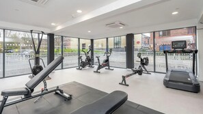 Ein Fitnessstudio mit unterschiedlichen Trainingsgeräten, großen Fenstern und Blick auf die Straße.