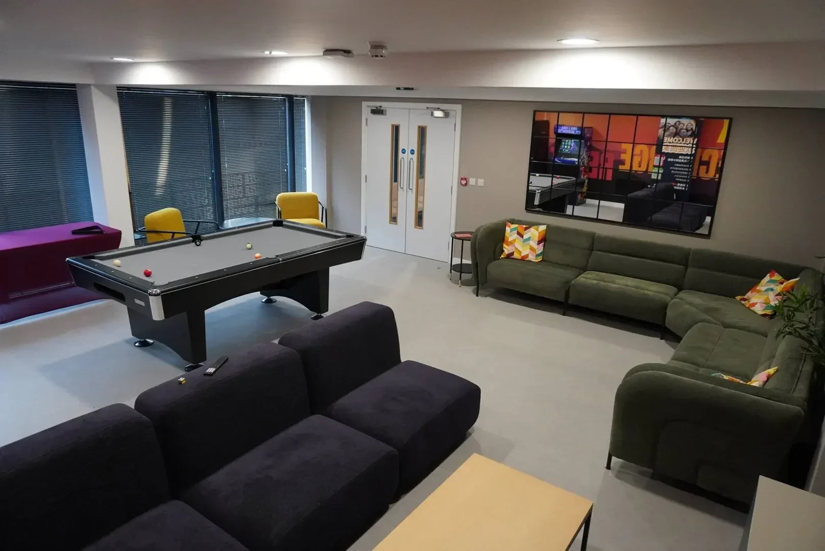 A room with a pool table, a sofa, and a small table.