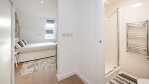 A bedroom with a bed, bedside table, and a window. - Student Only Sizer Court (Preston)