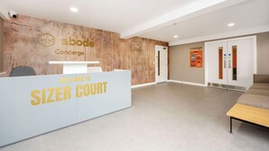 A reception area with a sign reading 'Welcome to Sizer Court' and a lounge area in the background. - Student Only Sizer Court (Preston)