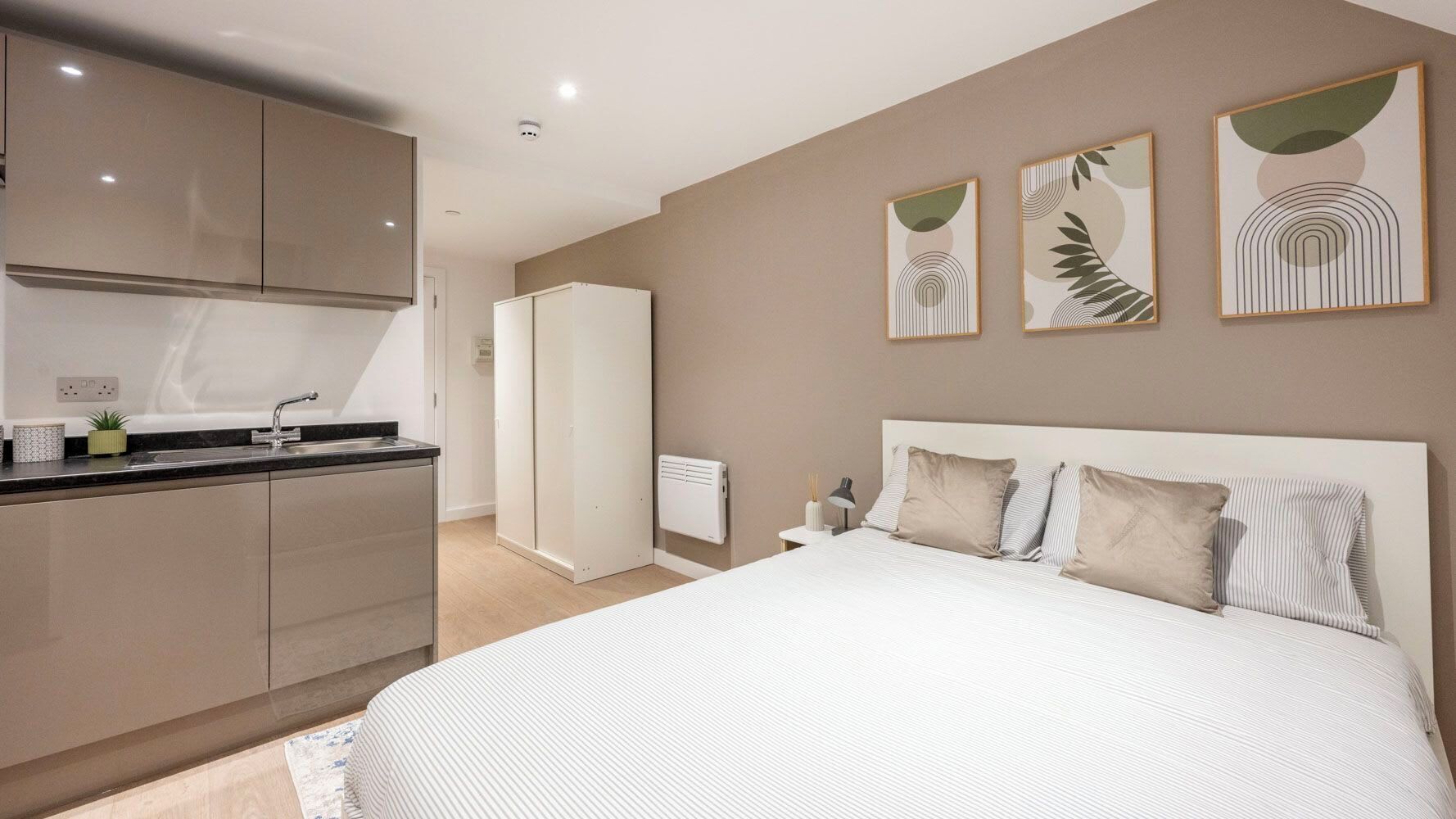 Een slaapkamer met een groot bed, een nachtkastje en een wandlamp.