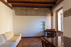 Ein Zimmer mit Holzboden, einer Couch, einem Esstisch mit Stühlen und einem Fenster mit Blick.