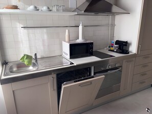Eine moderne Küche mit Spüle aus Edelstahl, einer Mikrowelle, einer Kaffeemaschine und einem Geschirrspüler.