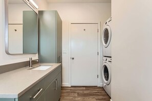 A compact laundry room with a sink, cabinets, and a door.
