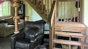 A wooden staircase with a unique design, a leather sofa, and a rustic decor. - Retreat to this quiet 1 bedroom cabin in the woods near a lake. (Wasilla)