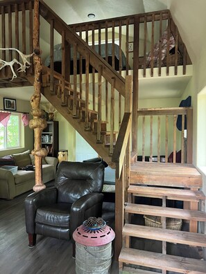 A wooden staircase with a unique design, a leather sofa, and a rustic decor. - Retreat to this quiet 1 bedroom cabin in the woods near a lake. (Wasilla)
