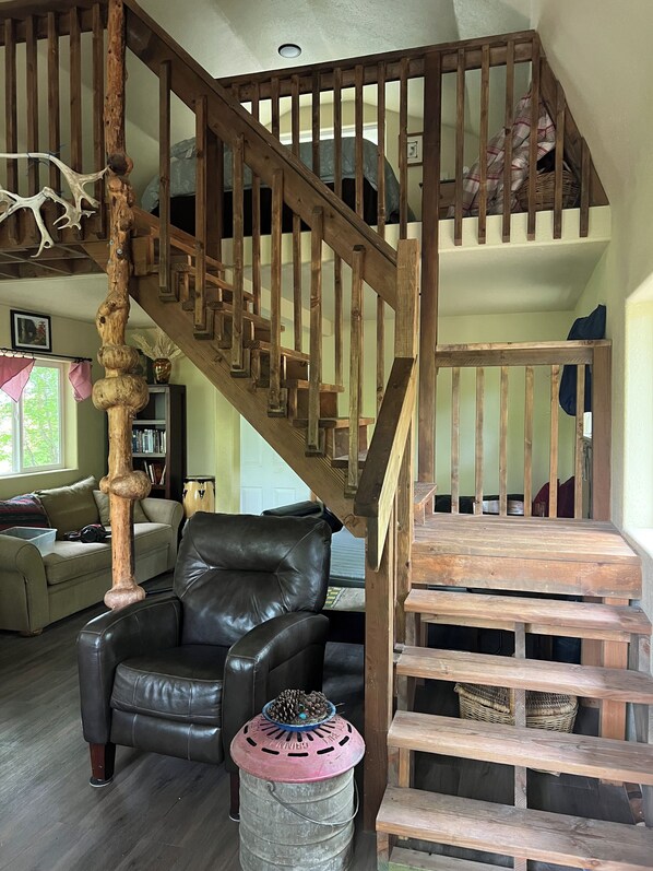 A wooden staircase with a unique design, a leather sofa, and a rustic decor. - Retreat to this quiet 1 bedroom cabin in the woods near a lake. (Wasilla)