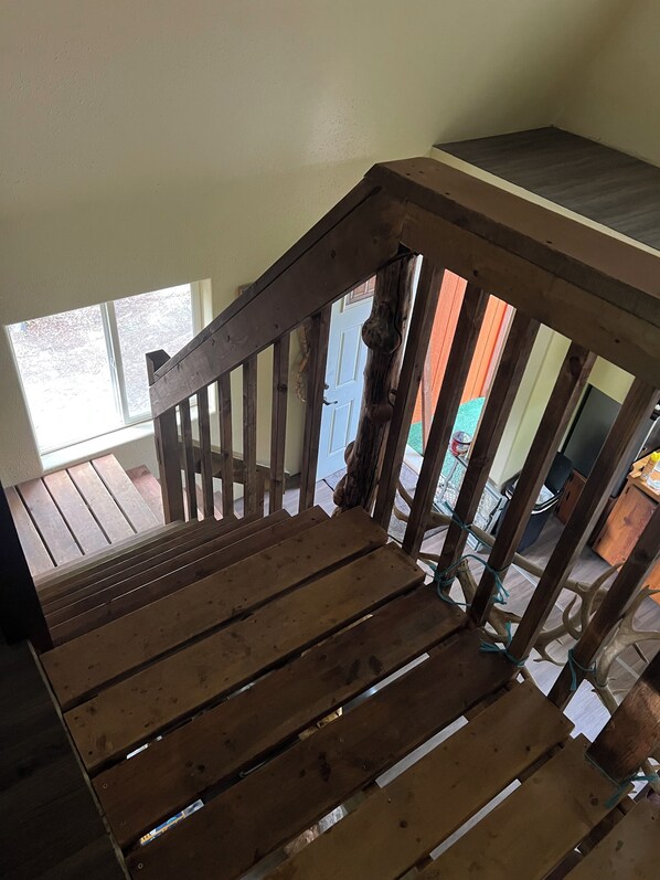 A wooden staircase with a handrail, leading to an upper floor. - Retreat to this quiet 1 bedroom cabin in the woods near a lake. (Wasilla)