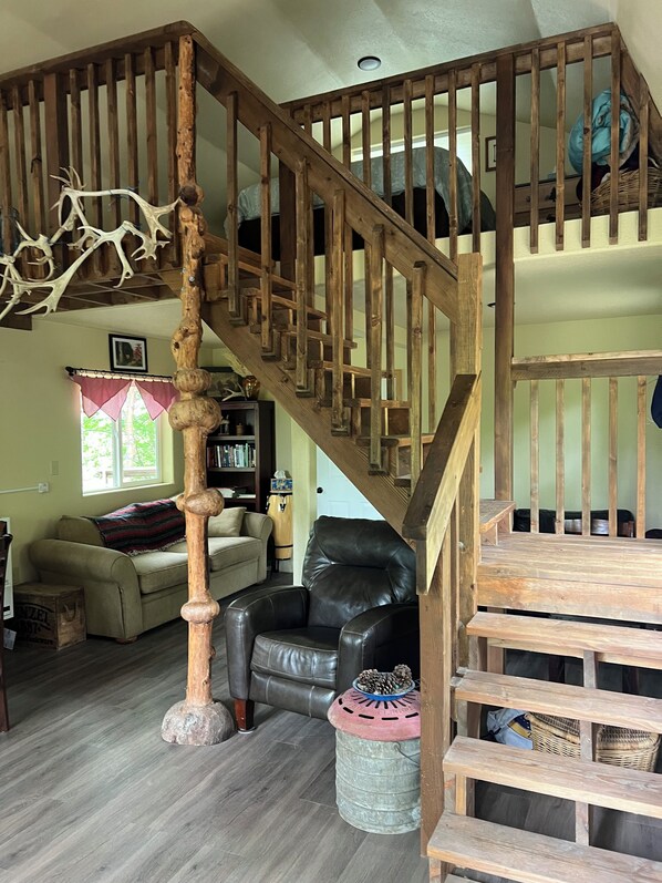 A wooden staircase with a unique design, a leather armchair, and a bookshelf in a living room setting.
