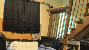 A bed with a blue quilt, a wooden chair, a wooden table, and a staircase. - Retreat to this quiet 1 bedroom cabin in the woods near a lake. (Wasilla)
