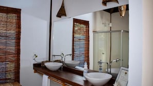 A bathroom with two sinks, a large mirror, and a glass shower enclosure. - Pousada Barra Suítes (Maraú)