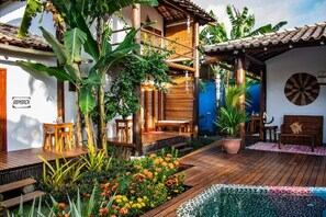 A wooden deck with a bench, a potted plant, and a dartboard on the wall. - Pousada Barra Suítes (Maraú)