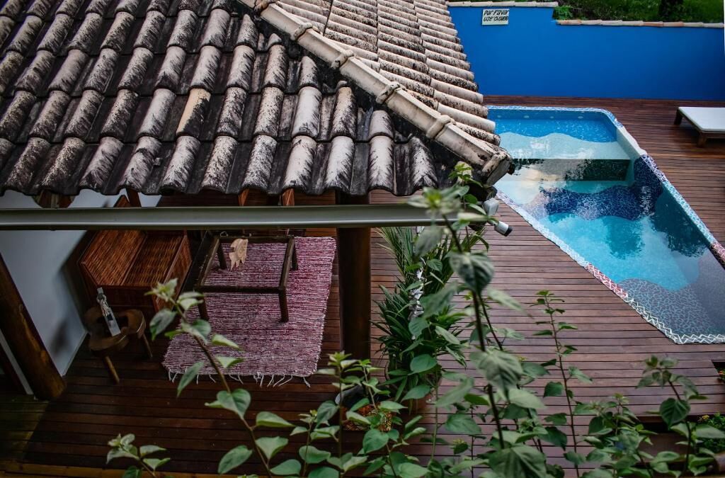 Een zwembad op het dak met een houten terras, een klein zitgedeelte en een blauwe muur op de achtergrond.